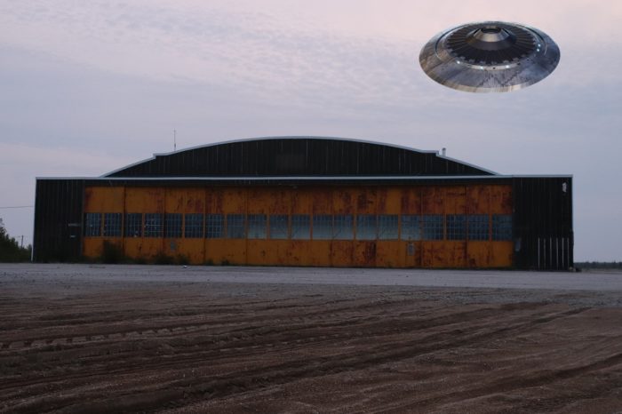 A depiction of a UFO over a military hangar