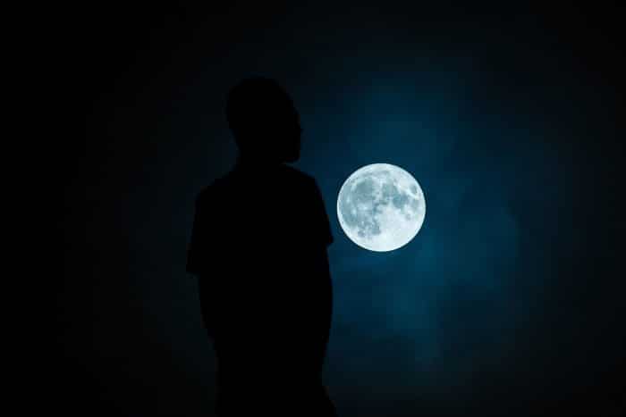 A dark figure under a full moon