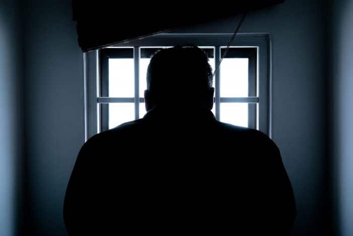 A picture of a dark figure in a prison cell