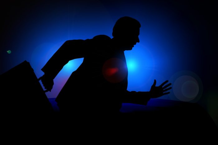A dark shadow figure running carrying a briefcase