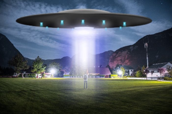 A depiction of a UFO shining a light on a person