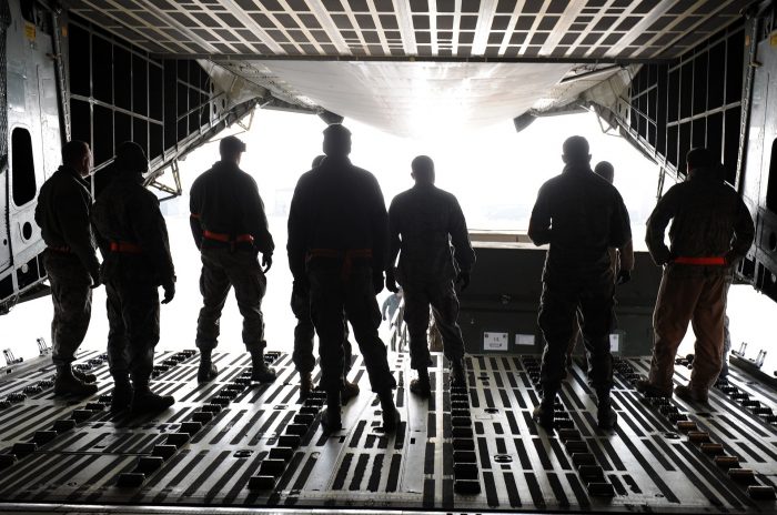 A picture of several men unloading cargo from the inside of the back of a plane