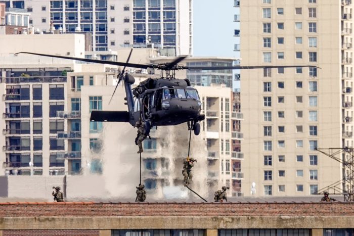 Picture of a Black Helicopter with soldiers descending from it on ropes