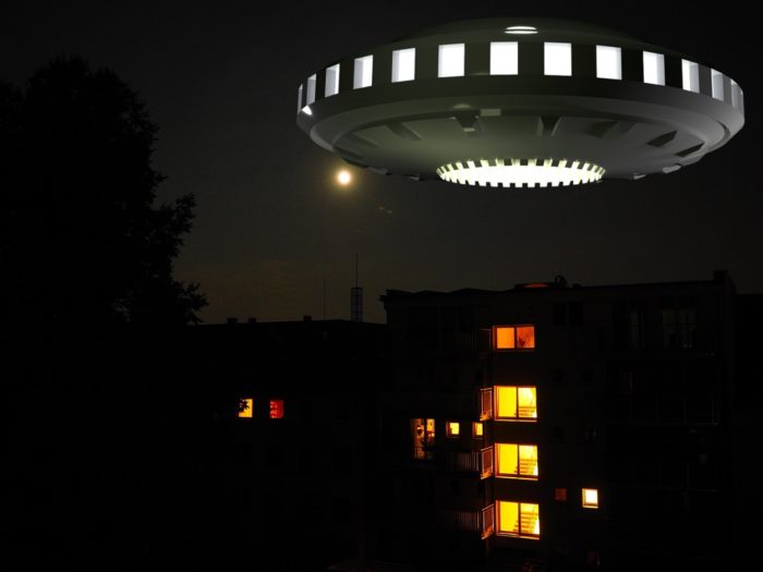 A depiction of a UFO hovering over apartments