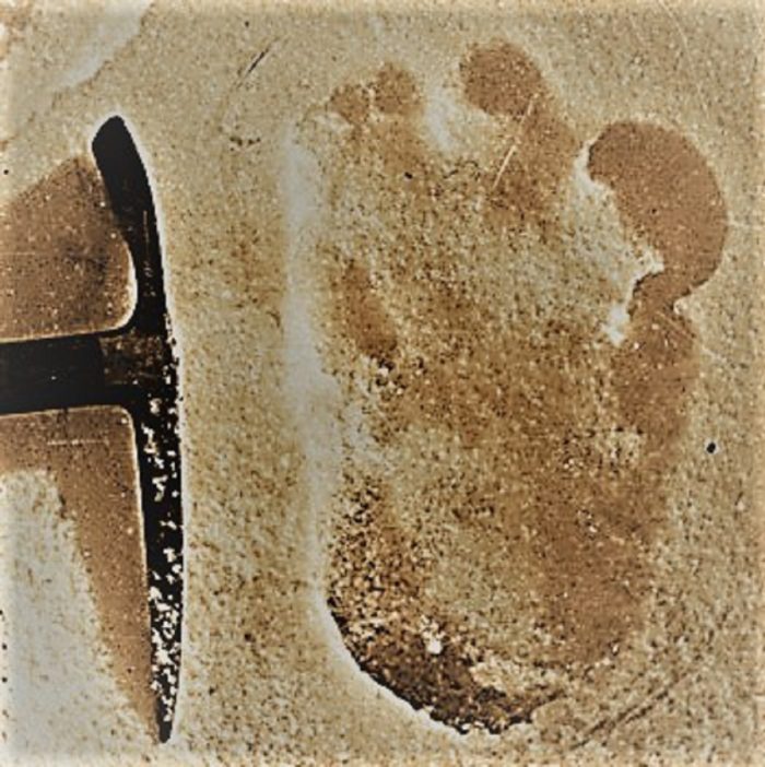 A huge footprint discovered in the snow with a pick ax next to it for comparison