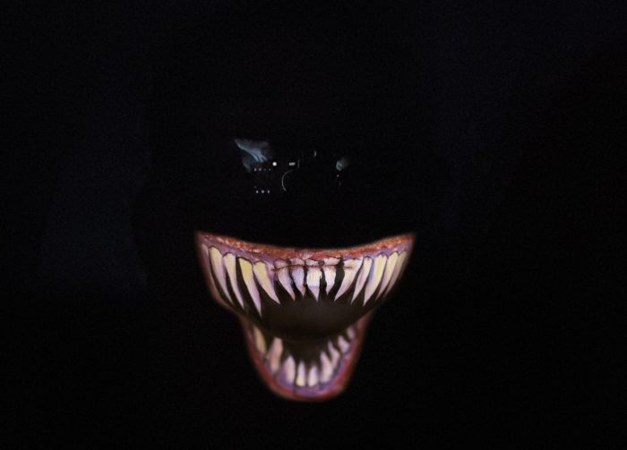 A depiction of a monsters face with sharp teeth