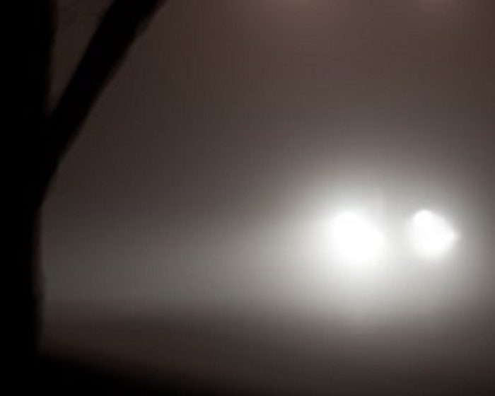 A pair of headlights emerging from the fog