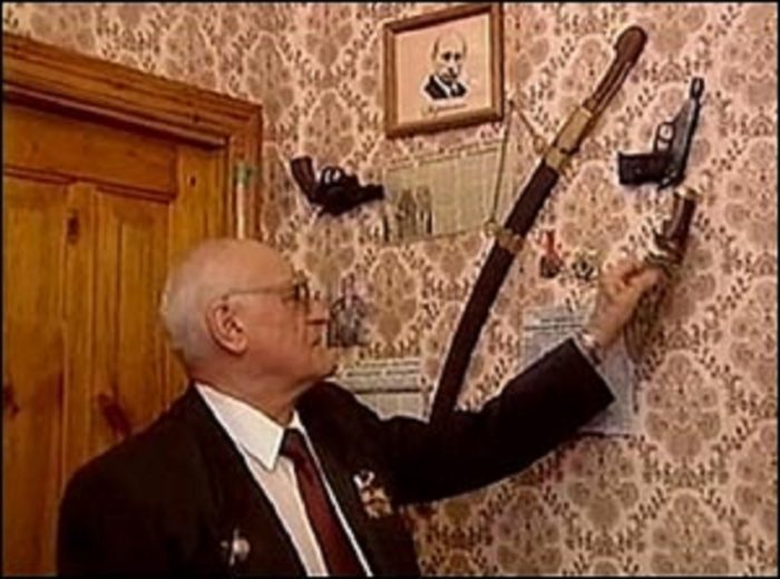 Picture of Eduard Koltsov pointing to a knife on his wall