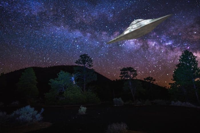 A depiction of a UFO flying over desert and woodland