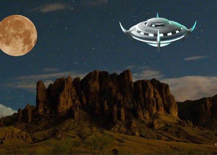 A depiction of a UFO hovering over desert at night