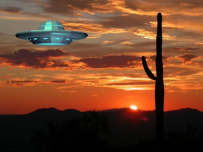 A superimposed UFO hovering over a desert at sunset