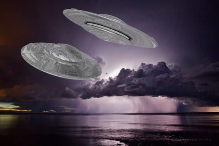 A depiction of UFOs flying over the water at night