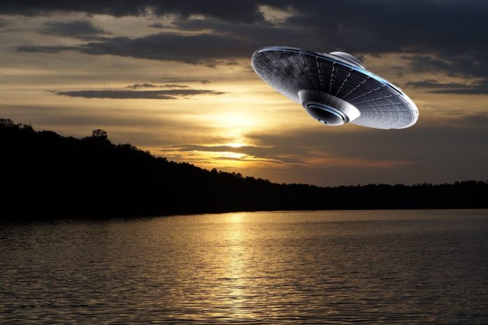 A superimposed UFO over a picture of a lake at sunset