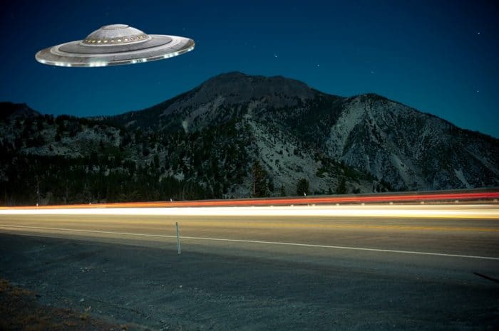 A superimposed UFO over a lonely highway