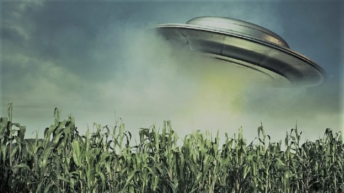 A depiction of a UFO over a field