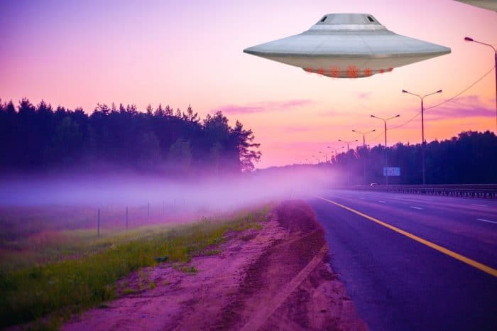 A depiction of a UFO over a lonely misty road