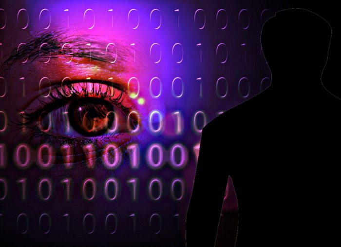 A black figure with a digital screen behind and an eye watching
