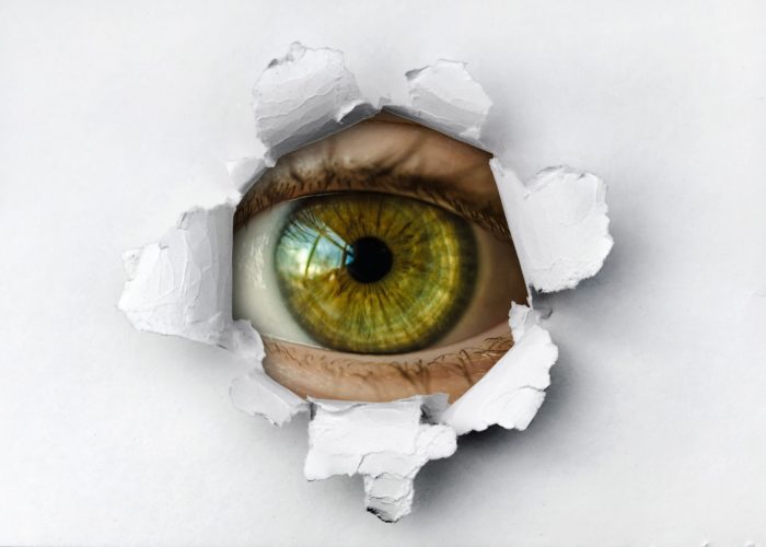 An eye watching through a hole in the wall
