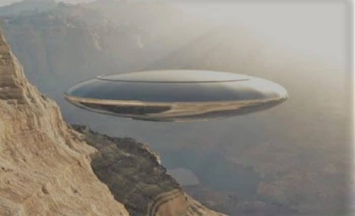 A depiction of a silver UFO over the mountains