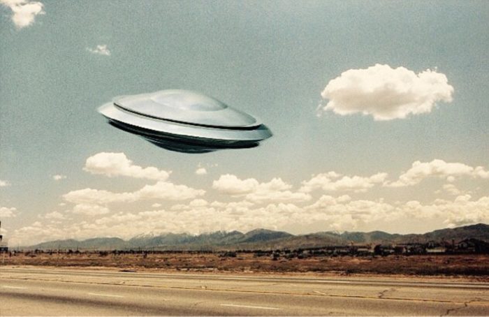 A depiction of a UFO over a lonely highway