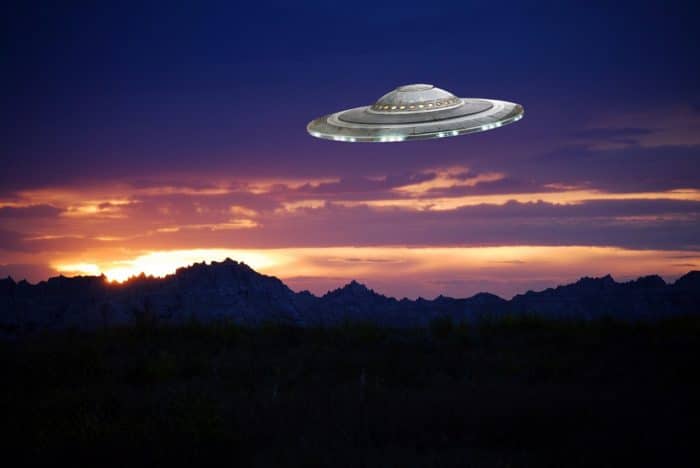 A depiction of a UFO over the mountains
