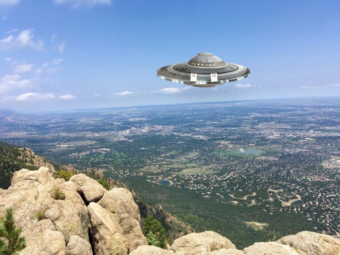 A depiction of a UFO hovering over the mountains