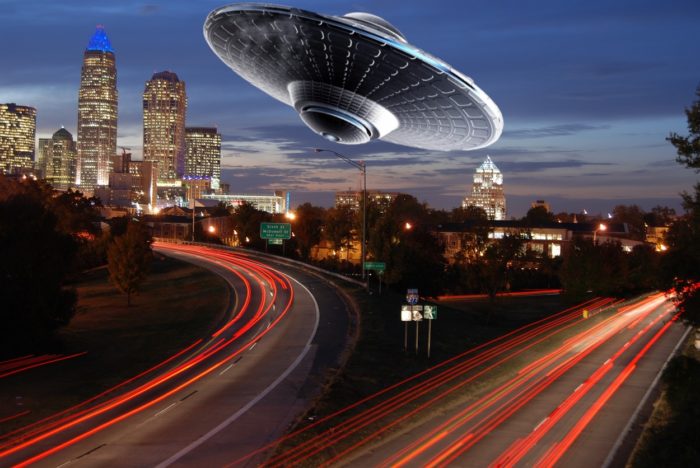 A superimposed UFO over a picture of a time lapsed highway