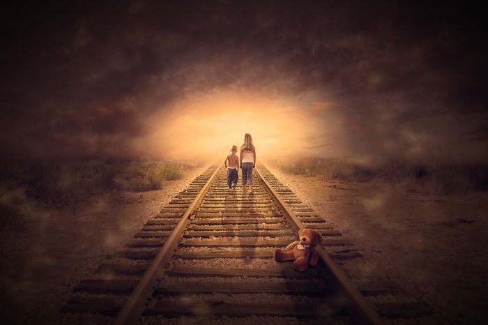 A picture of two children walking towards a mist on a lonely rail track
