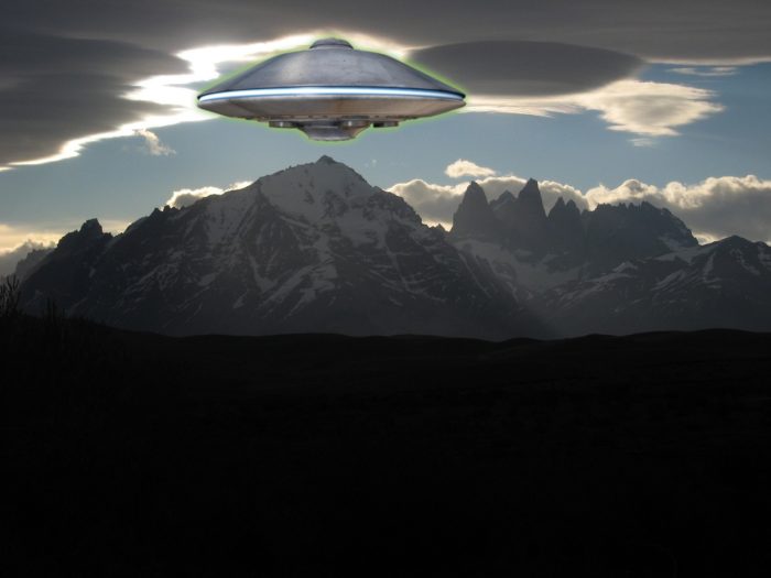 A depiction of a UFO over a mountain