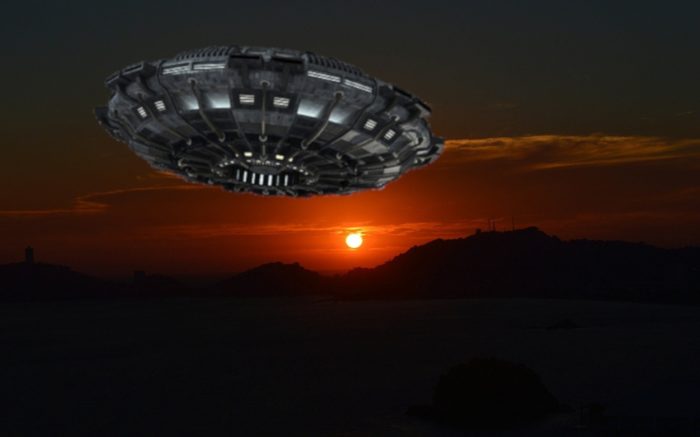 An image of a UFO flying over the mountains at night