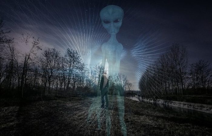 An image of a lone man in a field with an alien superimposed over the top
