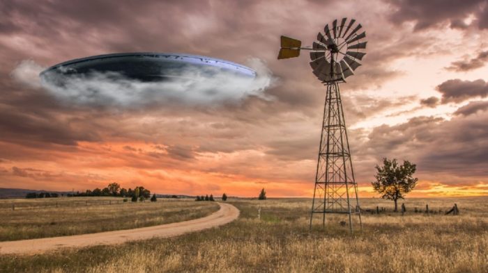 A superimposed UFO emerging from clouds over a picture of a lonely farm