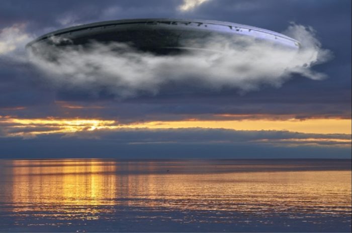 A superimposed UFO over a picture of ocean at sunset