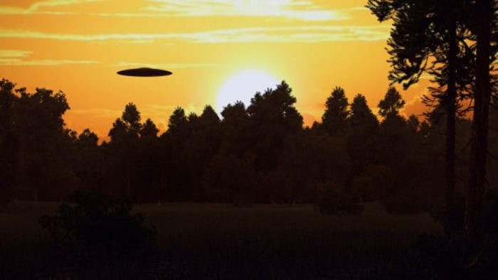 a depiction of a saucer shaped UFO over woodland at sunset