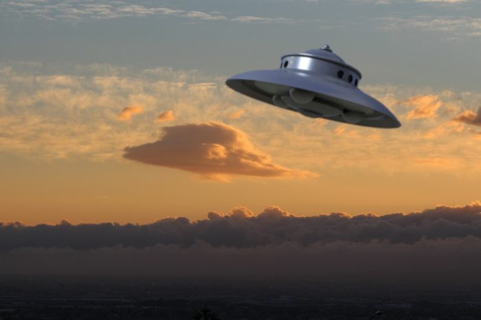 An image of a UFO in a cloudy sky at sunset