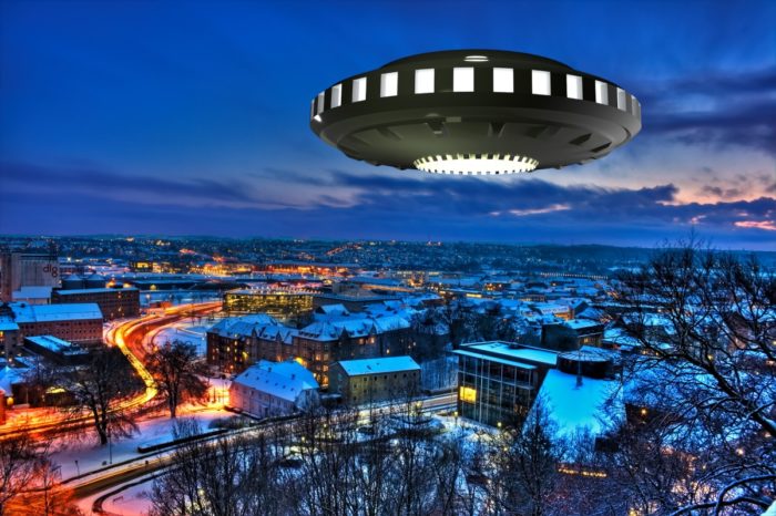 A superimposed UFO over a night scene of a snowy town