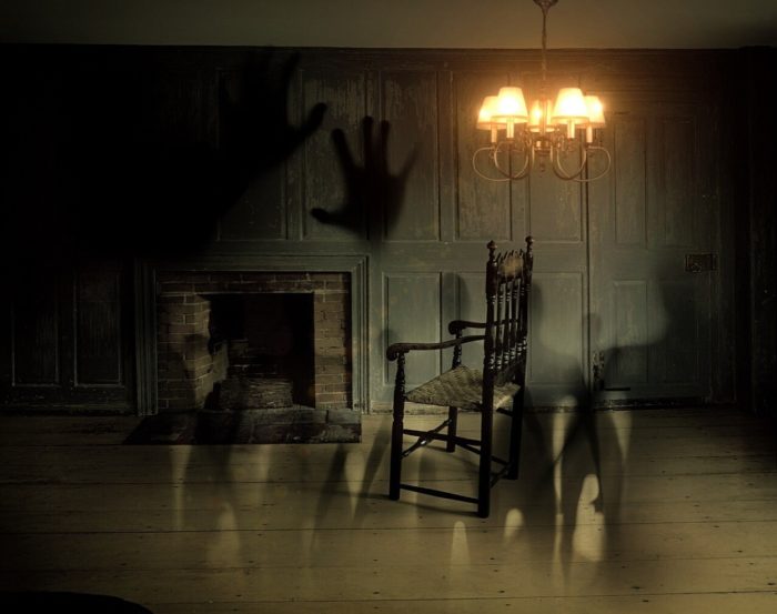 An old-fashioned room with ghostly hands and figures blended 