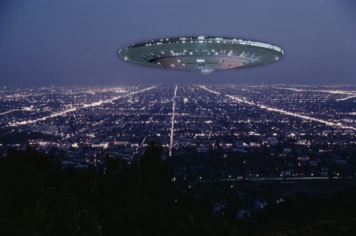 A superimposed UFO over an aerial shot of a city at night