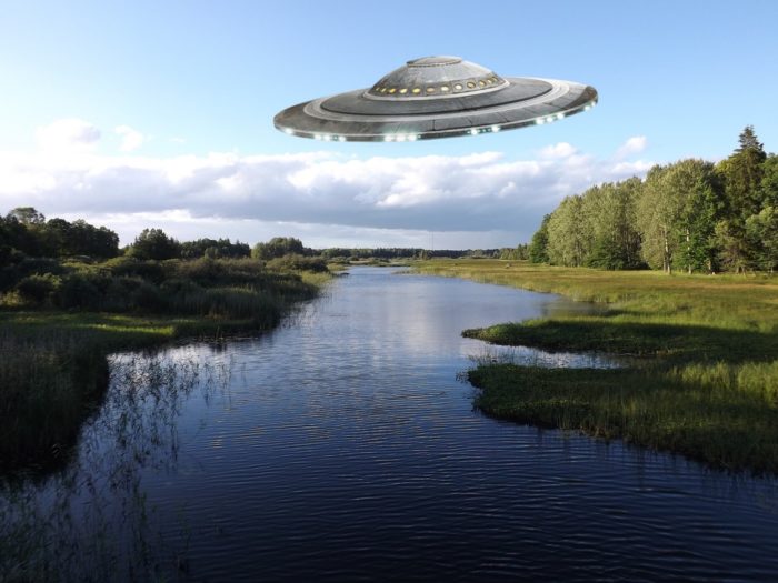 A superimposed UFO on a picture of a lake during the day