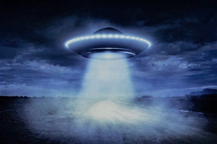 A superimposed UFO with a light shining toward the ground of a field 