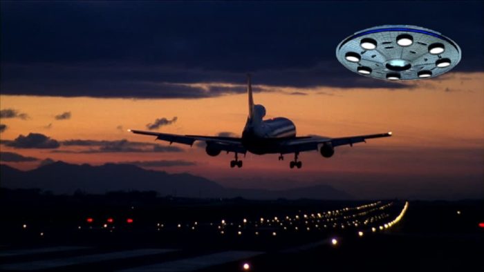 A superimposed UFO on a picture of a plane taking off from the runway at night