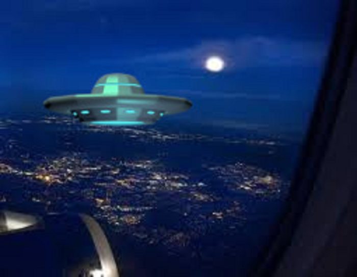 A view of the land from the plane window with a superimposed UFO 