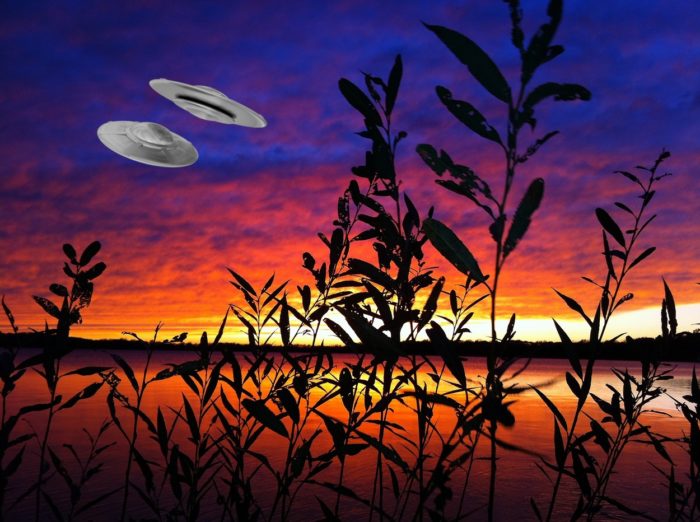 A picture of a two superimposed UFOs on lakeside scene at sunset