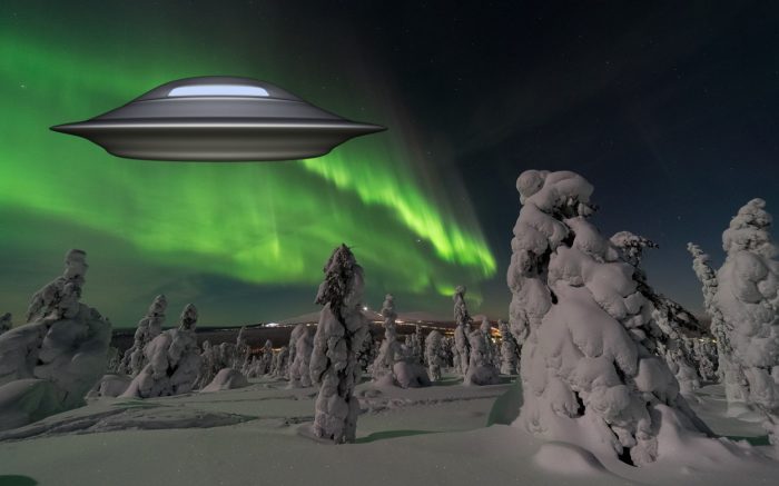 An image showing the aurora over snowy trees with a superimposed UFO over the top