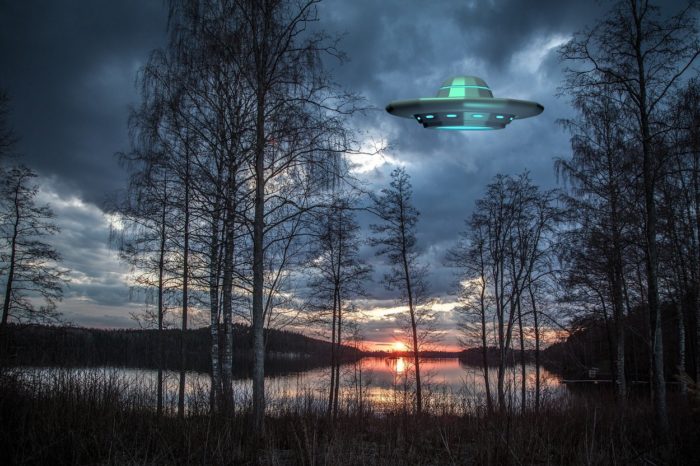 A superimposed UFO over a dawn image of a lake with trees