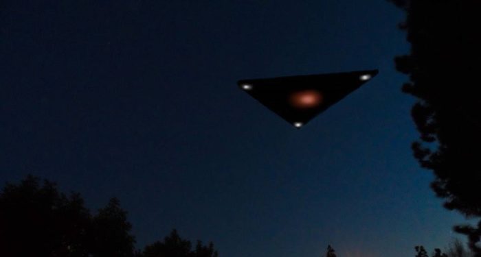 A black triangular UFO flying through the sky at night