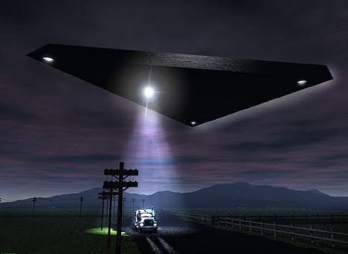 A depiction of a black triangular UFO hovering over a lone vehicle