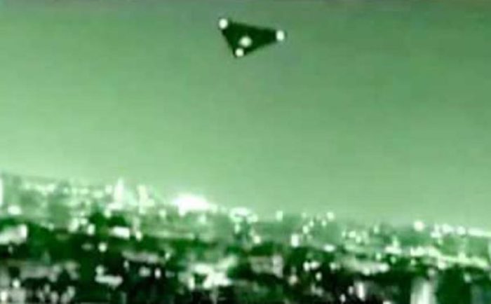 A picture showing a black triangle UFO at night over a city