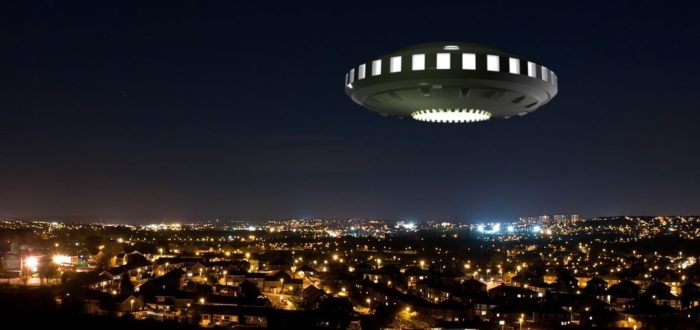 An image of a UFO over a picture of a city at night