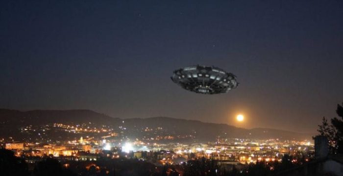 A superimposed UFO over a picture of a city at night